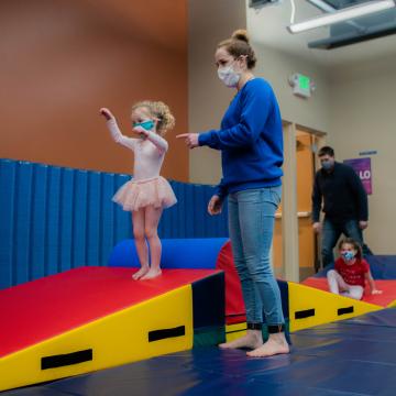 YMCA staff member working with young child in dance and gymnastics class YMCA staff member working with young child in dance and gymnastics class