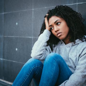 Teen sitting on the floor looking forlorn Teen sitting on the floor looking forlorn