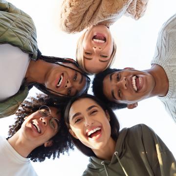 Five smiling teens standing in a circle, looking down at the camera Five smiling teens standing in a circle, looking down at the camera
