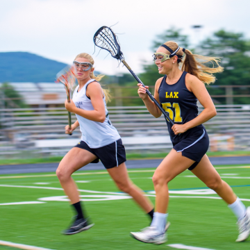 Teens running across a lacrosse field Teens running across a lacrosse field