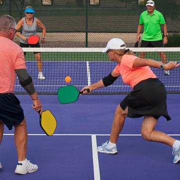 Group of four older adults playing pickleball outdoors Group of four older adults playing pickleball outdoors