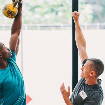 Male trainer teaching male client how to lift kettlebell Male trainer teaching male client how to lift kettlebell