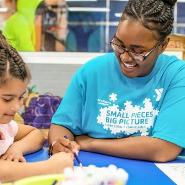 Kids' Club staff member doing crafts with happy young children Kids' Club staff member doing crafts with happy young children