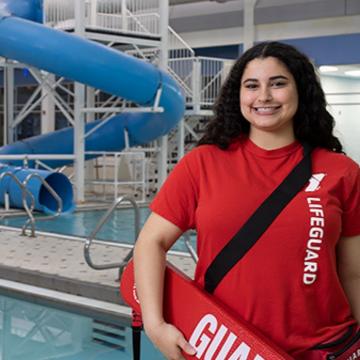 Smiling lifeguard standing next to family pool Smiling lifeguard standing next to family pool