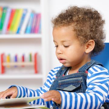Toddler sitting in chair reading a book Toddler sitting in chair reading a book