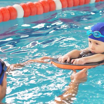 Child in the pool swimming to an instructor Child in the pool swimming to an instructor