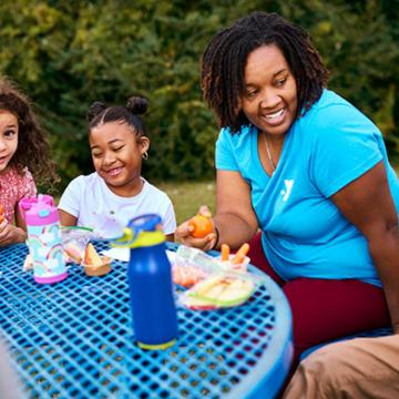 YMCA staff member outside with kids at YMCA summer camp YMCA staff member outside with kids at YMCA summer camp