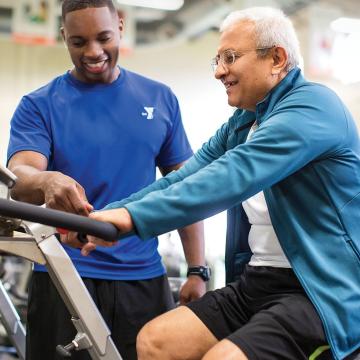 Trainer working with a man on a cycling bike Trainer working with a man on a cycling bike